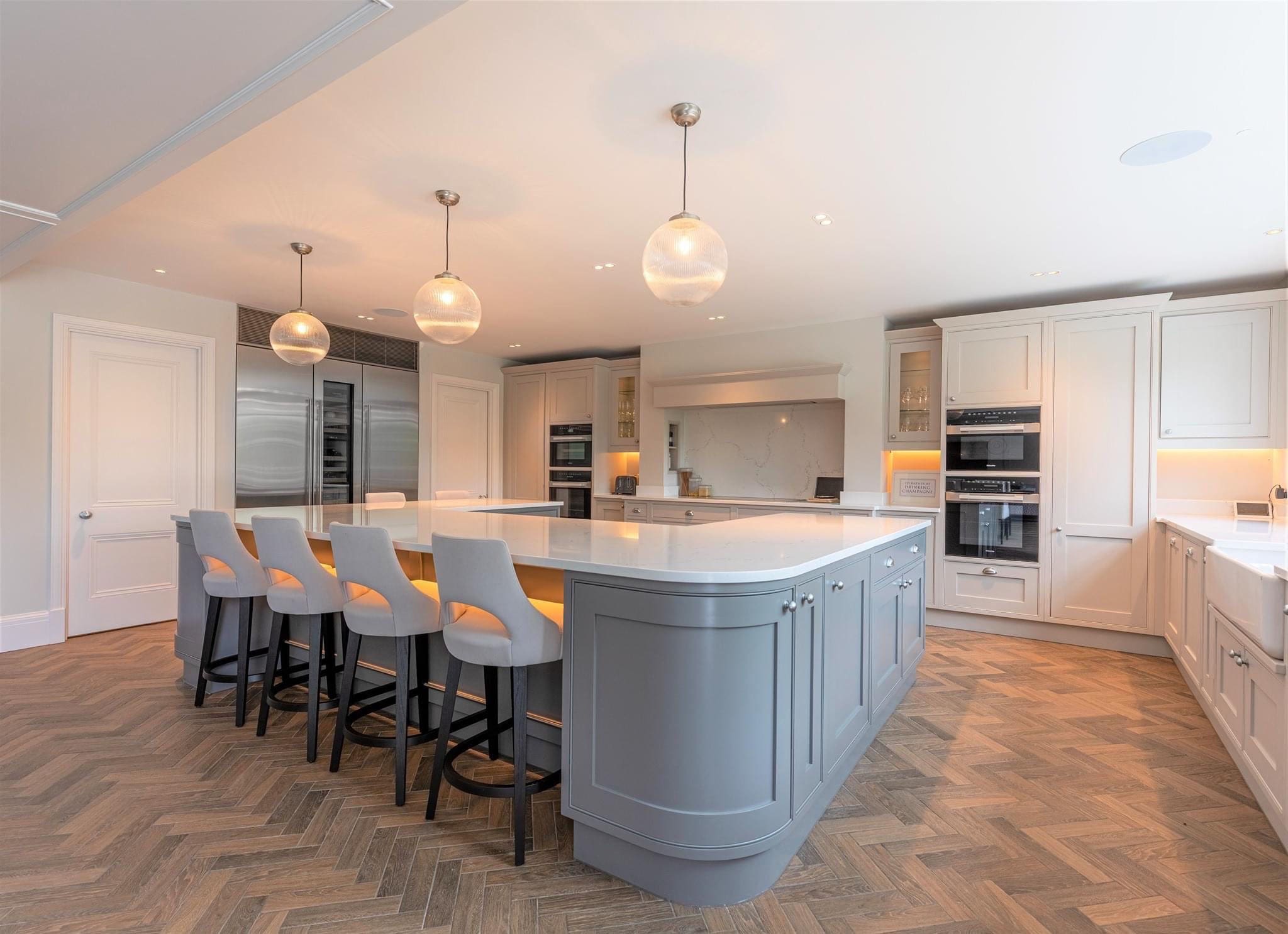 large central kitchen island and bar stools with white kitchen units